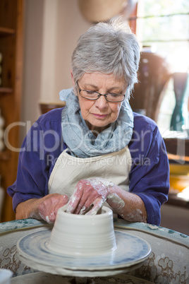 Attentive female potter making pot