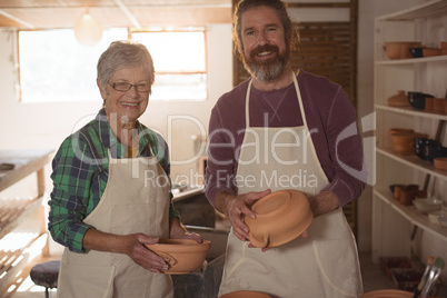 Male and female potter holding pots