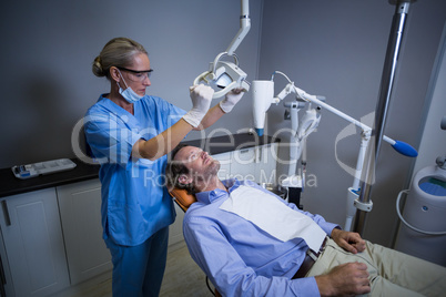 Dentist assistant adjusting light over patients mouth