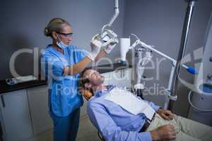 Dentist assistant adjusting light over patients mouth