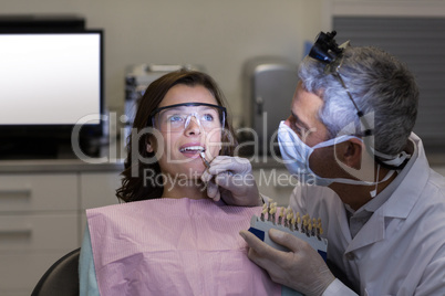 Dentist examining female patient with teeth shades