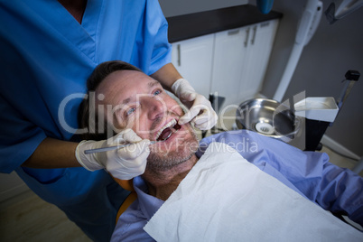 Dentist examining a young patient with tools