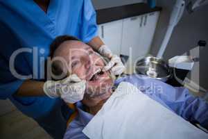 Dentist examining a young patient with tools