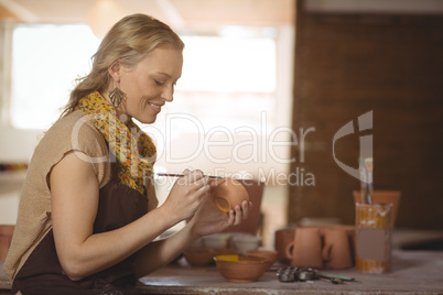 Beautiful female potter painting on bowl