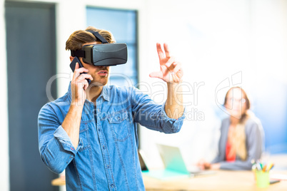 Young man using the virtual reality headset while talking on pho