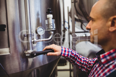 Manufacturer adjusting pressure gauge in brewery