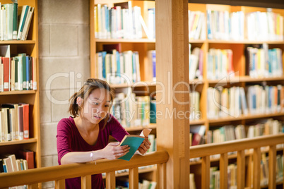 Young woman reading book in library