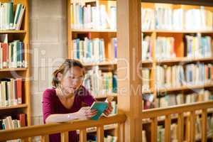 Young woman reading book in library