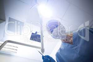 Dental assistant in surgical mask holding dental tools