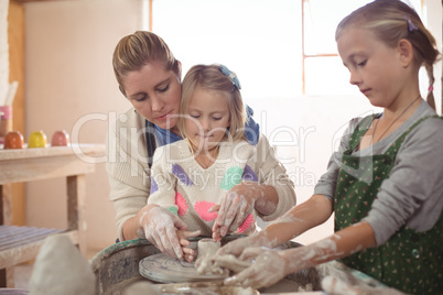 Female potter assisting girls