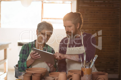 Male and female potter using digital tablet