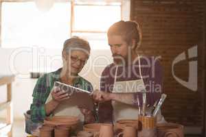 Male and female potter using digital tablet