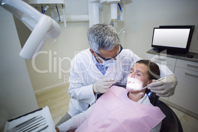 Dentist examining a patient with tools