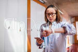 Young woman checking time while using mobile phone