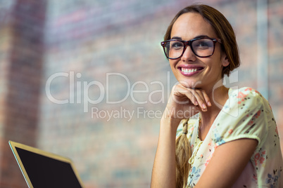 Smiling business executive with hand on chin in office