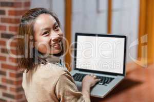 Young woman using laptop in corridor