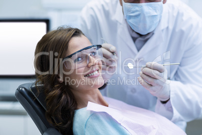 Dentist examining a female patient with tools