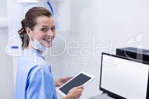 Smiling dental assistant holding digital tablet