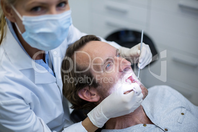 Dentist examining a patient with tools