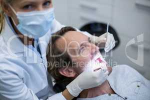 Dentist examining a patient with tools