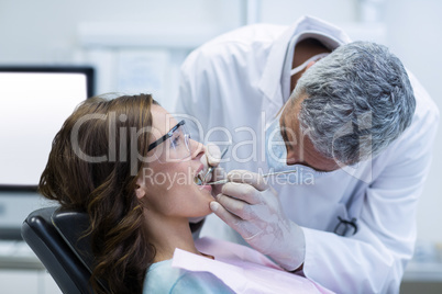 Dentist examining a female patient with tools