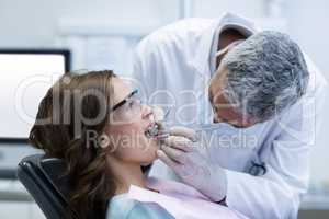 Dentist examining a female patient with tools