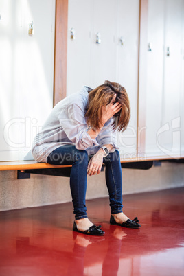 Tensed woman sitting in locker room