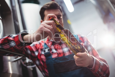 Manufacturer examining beer bottle at brewery