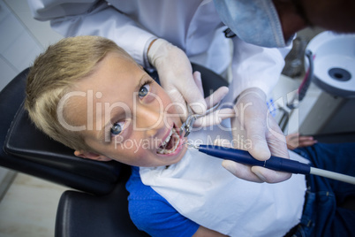 Dentist examining a young patient with tools