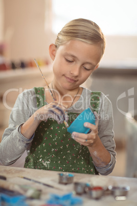 Attentive girl painting on bowl