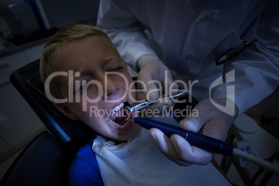 Dentist examining a young patient with tools