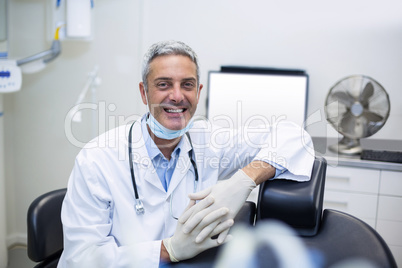 Portrait of confident dentist sitting beside chair