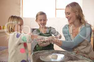 Woman having fun with girls while making pottery
