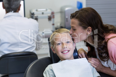 Mother kissing her son while dental examination