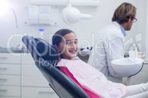 Smiling young patient sitting on dentists chair