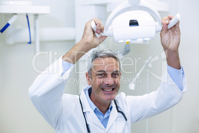 Smiling dentist adjusting light