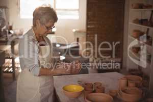 Female potter pouring watercolor in bowl