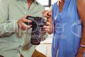 Graphic designer showing photo to colleague on digital camera
