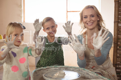 Woman and girls showing hands in pottery shop