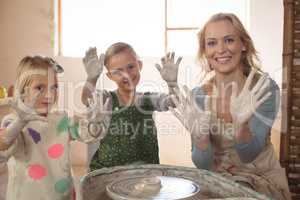 Woman and girls showing hands in pottery shop