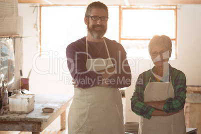 Portrait of male and female potter standing with arms crossed