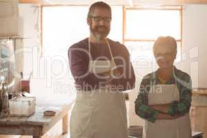 Portrait of male and female potter standing with arms crossed