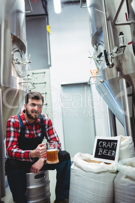 Manufacturer with beer glass while sitting at brewery