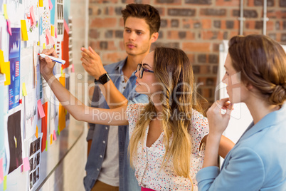 Business executive writing on sticky notes on whiteboard