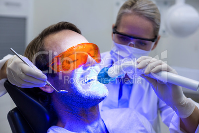 Female dentist examining male patient with tools