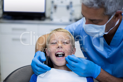 Dentist examining a young patient with tools