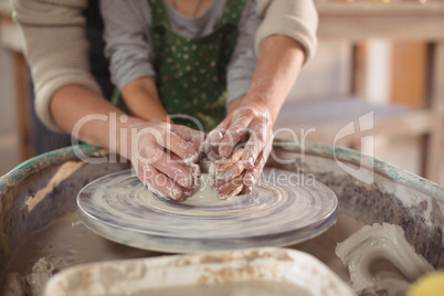 Mid section of female potter assisting girls