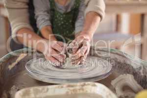 Mid section of female potter assisting girls