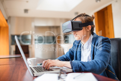 Young woman in virtual reality glasses using laptop
