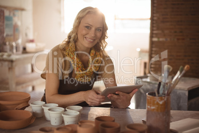 Beautiful female potter using digital tablet